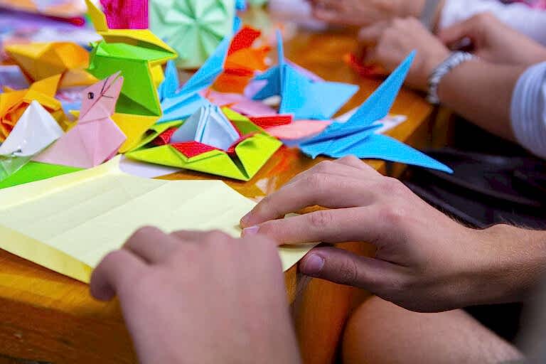 Hands of a man creating a colored origami paper