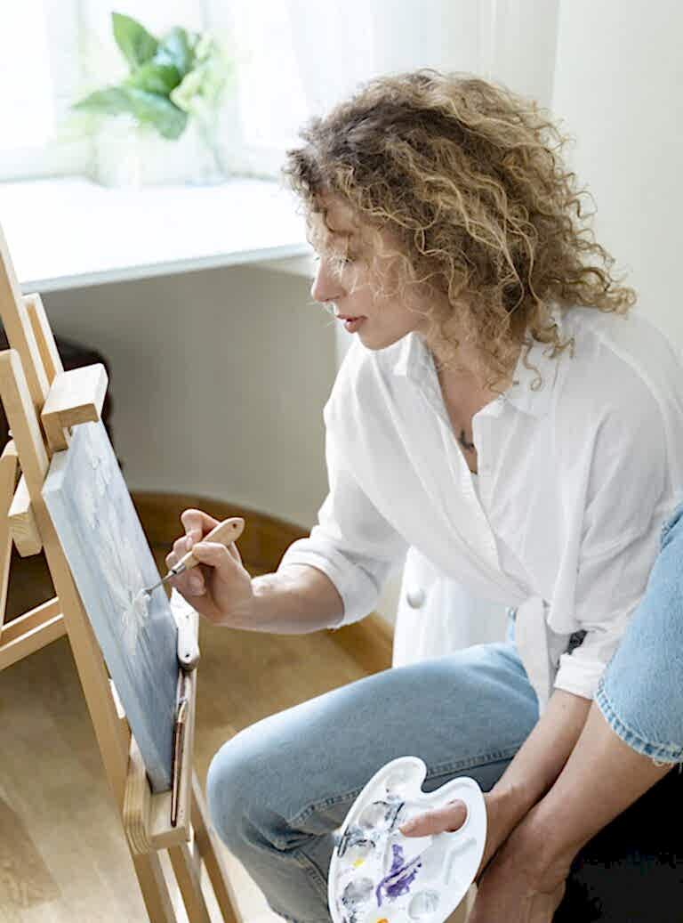 side-view-curly-haired-woman-painting-home